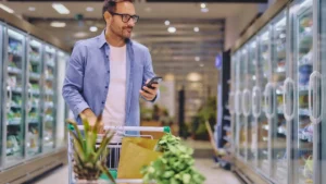 Persona usando su celular mientras compra en un supermercado